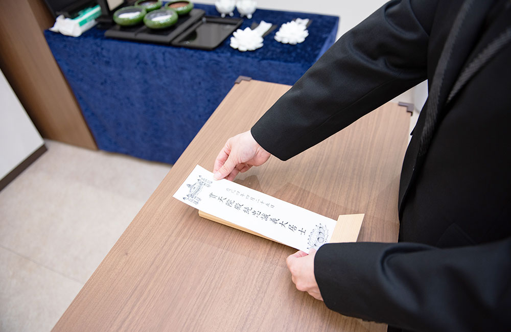 白木のお位牌に戒名用紙を貼る様子
